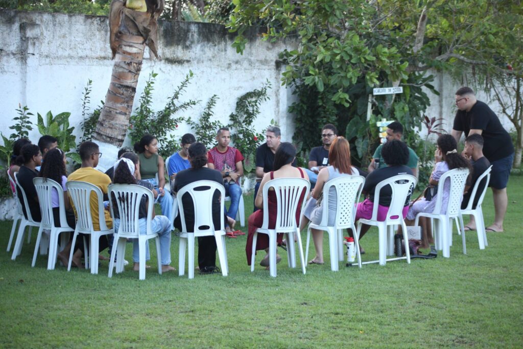Grupo de retiro reunido em círculo de cadeiras na área verde da Chácara da Serra