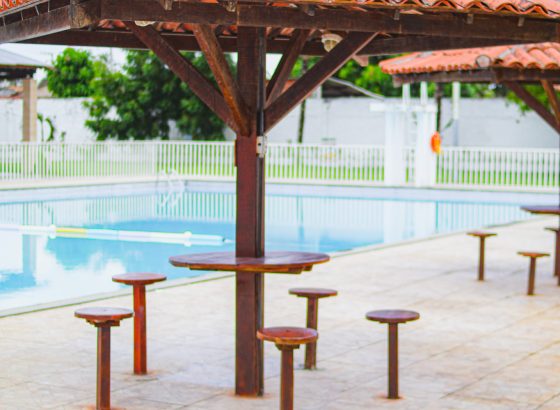 Piscina com quiosque coberto de mesas e bancos na borda