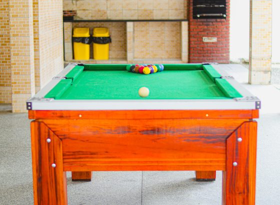 Mesa de sinuca em área coberta ao lado da churrasqueira de tijolos