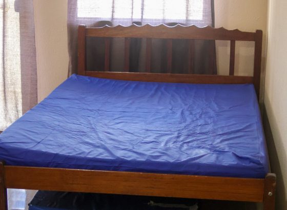 Quarto com cama de casal de madeira e cama auxiliar retrátil embaixo
