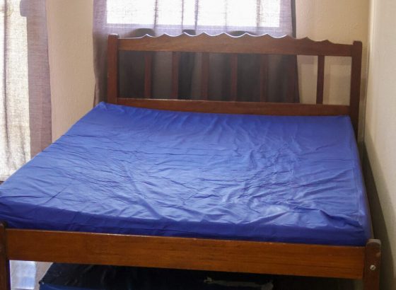Quarto com cama de casal de madeira e cama auxiliar retrátil embaixo